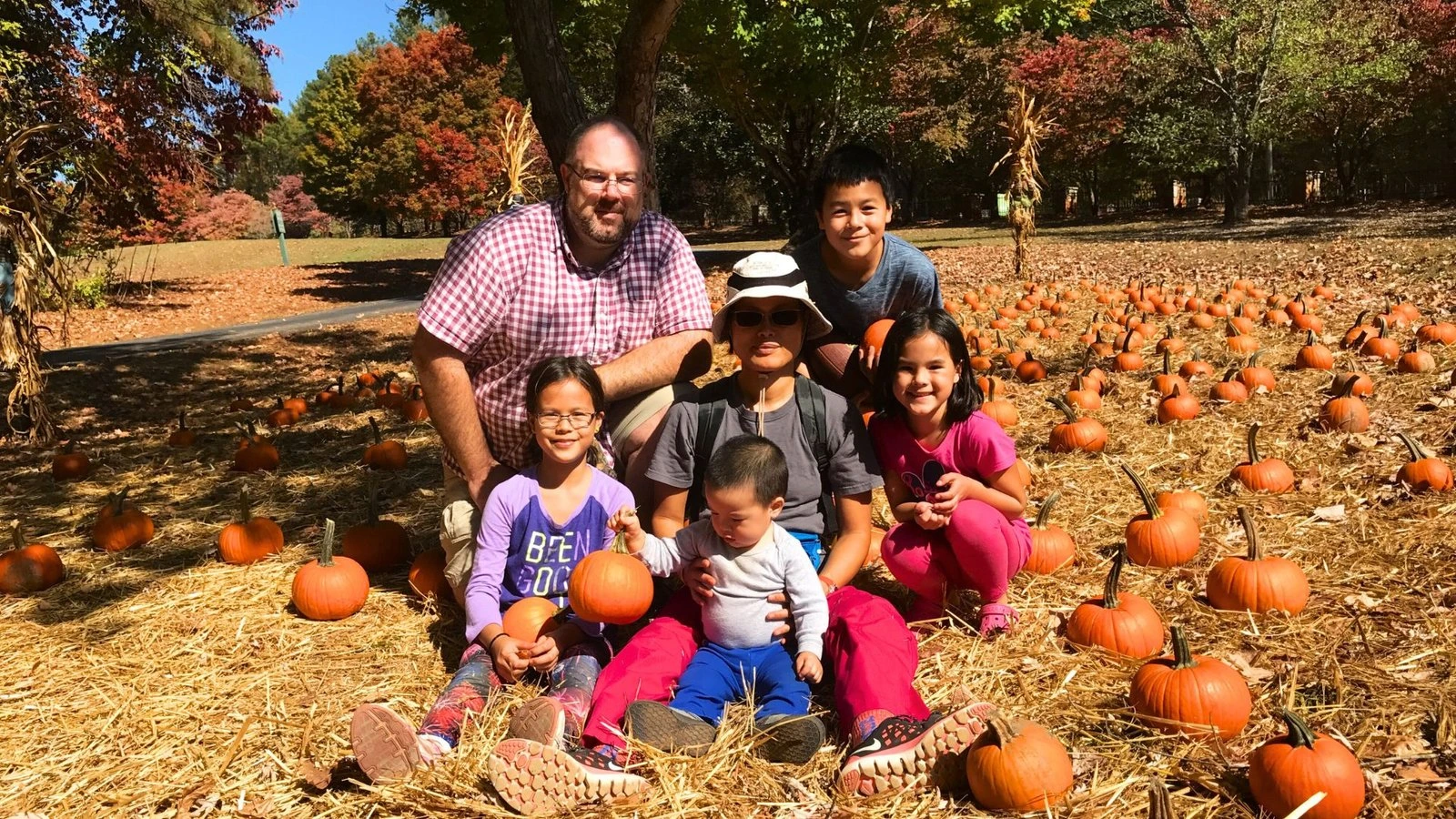 Photo of a family at a campground fall festival surrounded by pumpkins, highlighting seasonal family camping fun.
